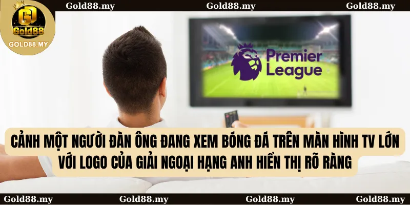 Cảnh một người đàn ông đang xem bóng đá trên màn hình TV lớn với logo của giải Ngoại hạng Anh hiển thị rõ ràng